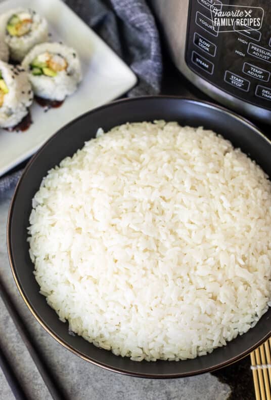 Bowl of Instant Pot Sushi Rice next to an instant pot and sushi rolls.