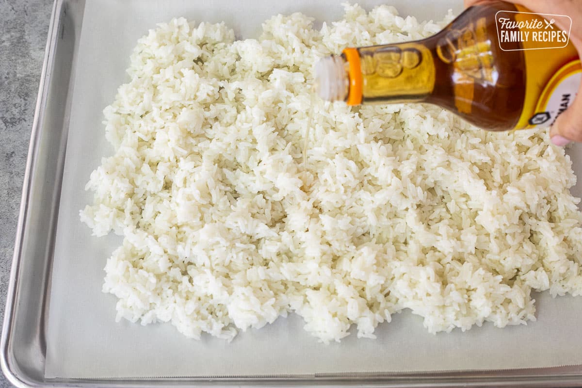 Pouring seasoned rice vinegar on cooled instant pot sushi rice.