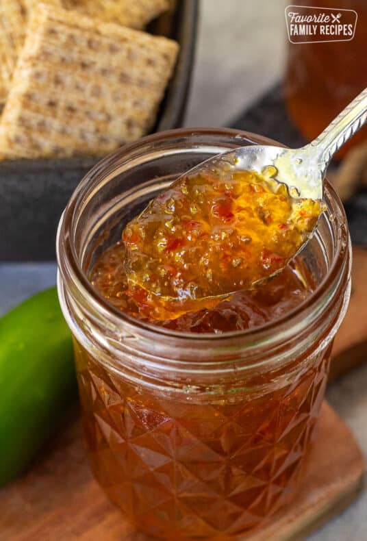 Spoon of Jalapeño pepper jelly coming out of a jar.