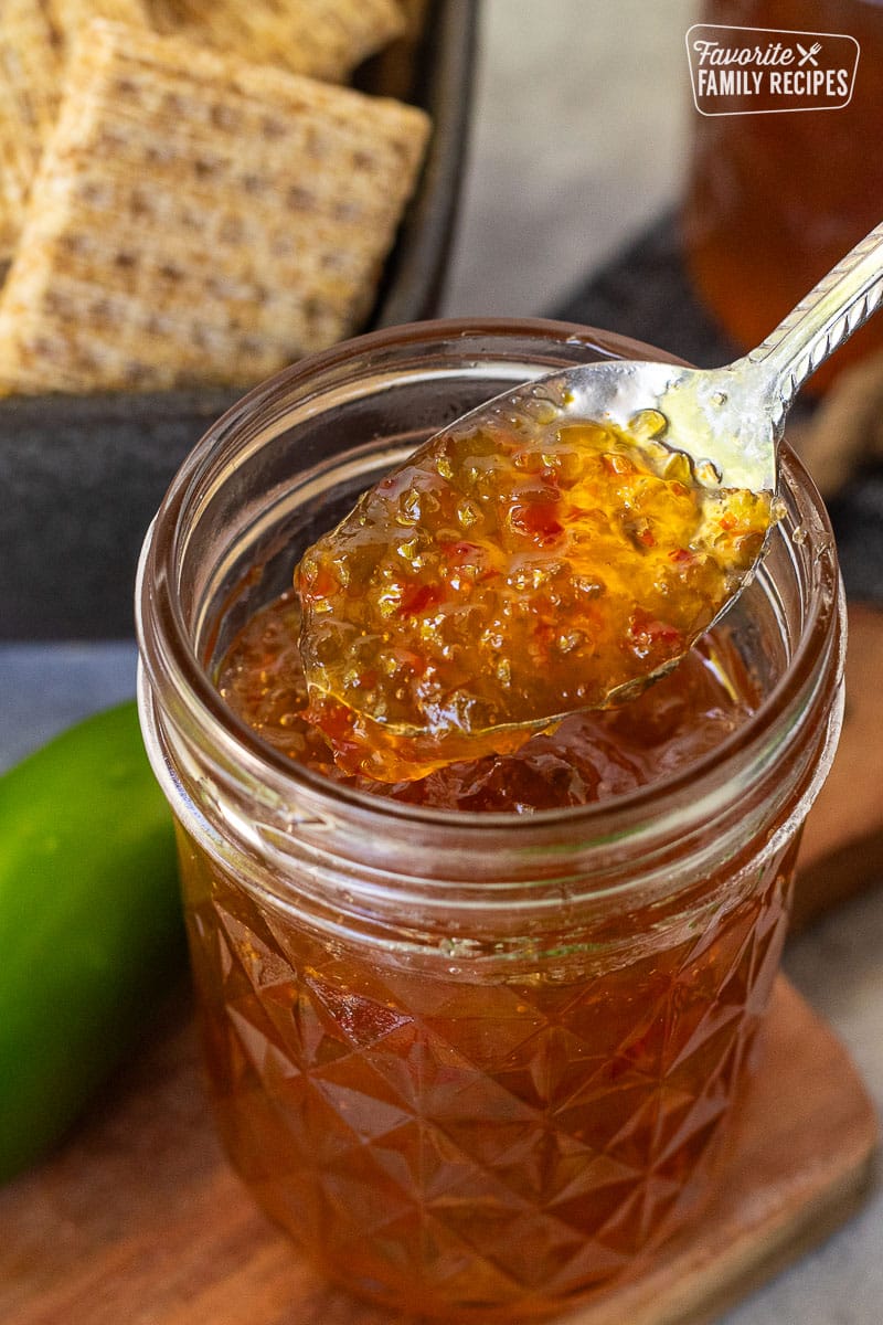 Spoon of Jalapeño pepper jelly coming out of a jar.