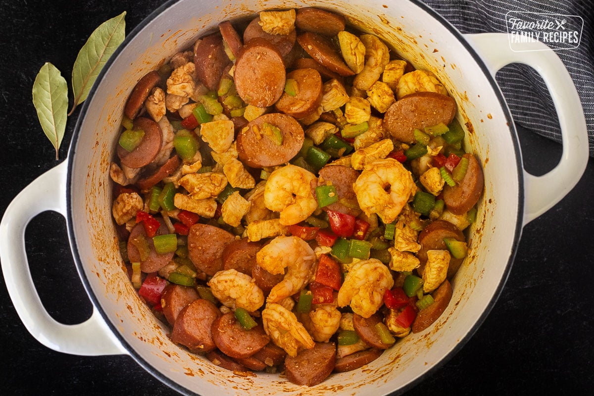Dutch oven with sausage, chicken, shrimp, vegetables and seasonings.