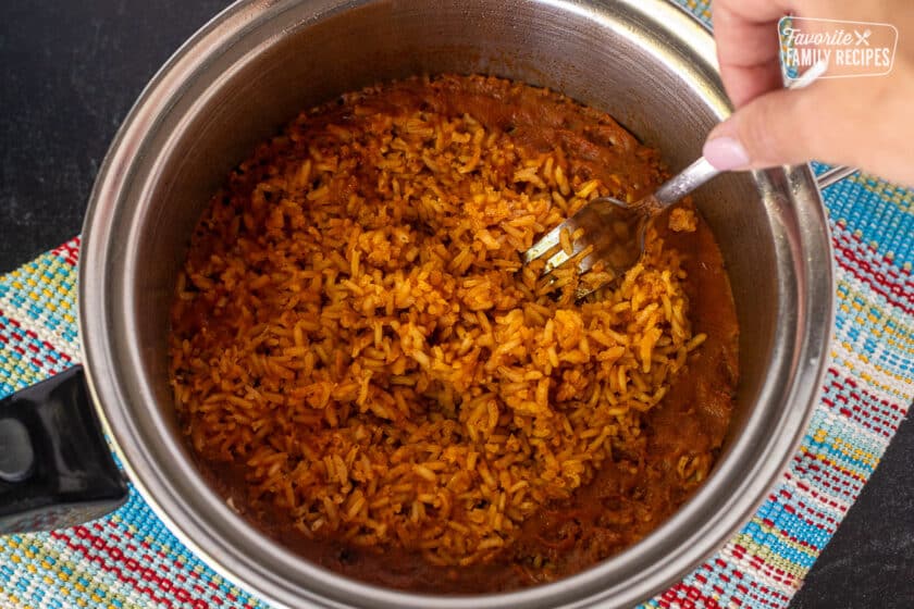 A recipe step visual of fluffing Mexican rice after it has simmered.