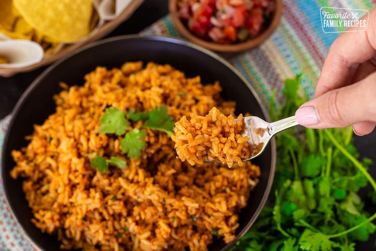 Fork with Mexican Rice held over a bowl of rice.