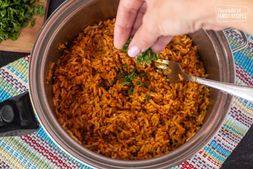 Mexican rice recipe step of sprinkling chopped cilantro on cooked Mexican rice.