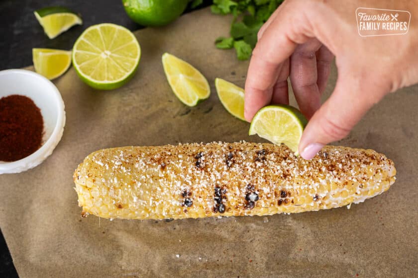 Squeezing lime onto grilled Mexican Street Corn.