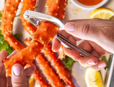 Cracking open a piece of crab legs with a cracking tool.