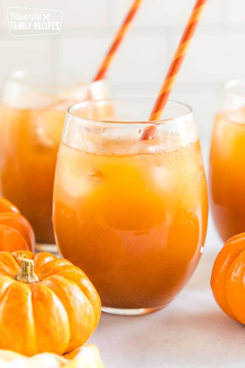 A glass of pumpkin juice with ice and a straw