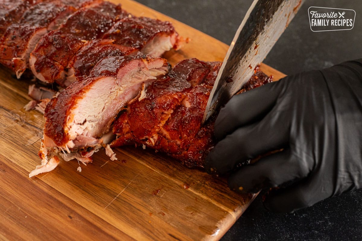 Cutting the rack of ribs with a knife on a cutting board.