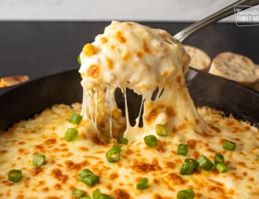 Pulling out a scoop of Corn Cheese from the skillet.