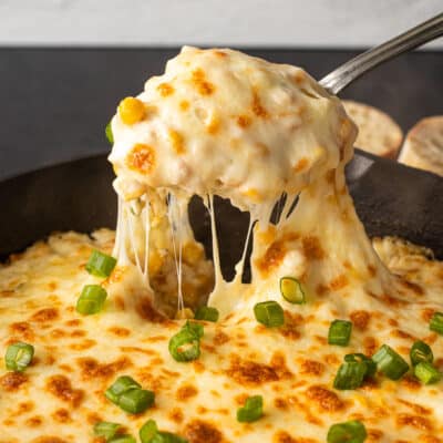 Pulling out a scoop of Corn Cheese from the skillet.