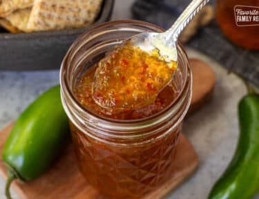Spoon of jalapeño pepper jelly on a spoon over the glass canning jar.