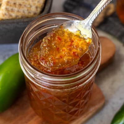 Spoon of jalapeño pepper jelly on a spoon over the glass canning jar.