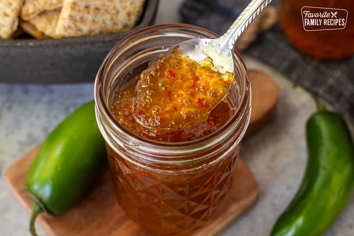 Spoon of jalapeño pepper jelly on a spoon over the glass canning jar.