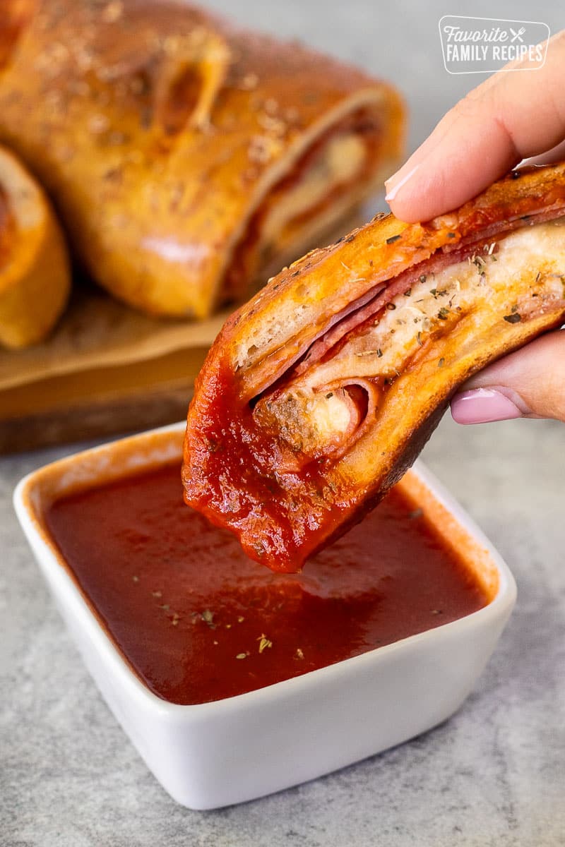 Dipped piece of Stromboli in a dish of pizza sauce.