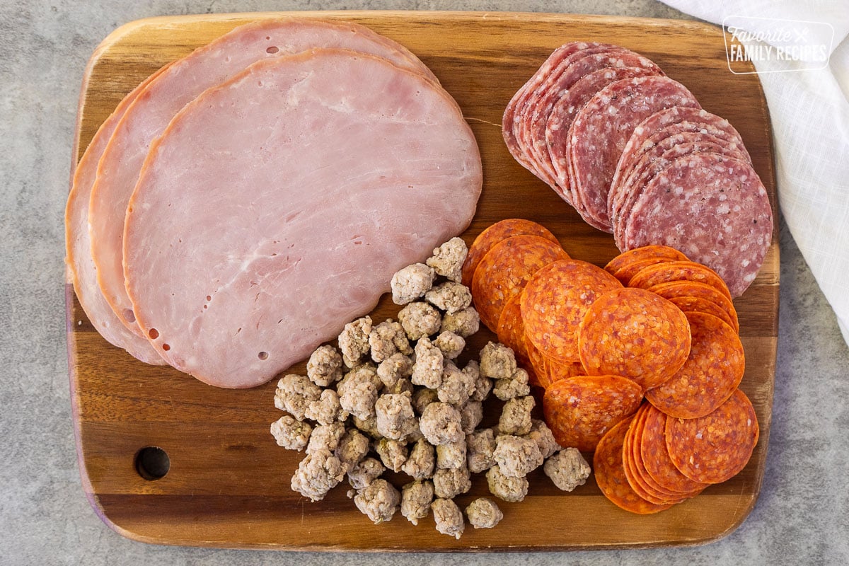 Tray with deli ham, pepperoni, salami and cooked Italian sausage pieces.