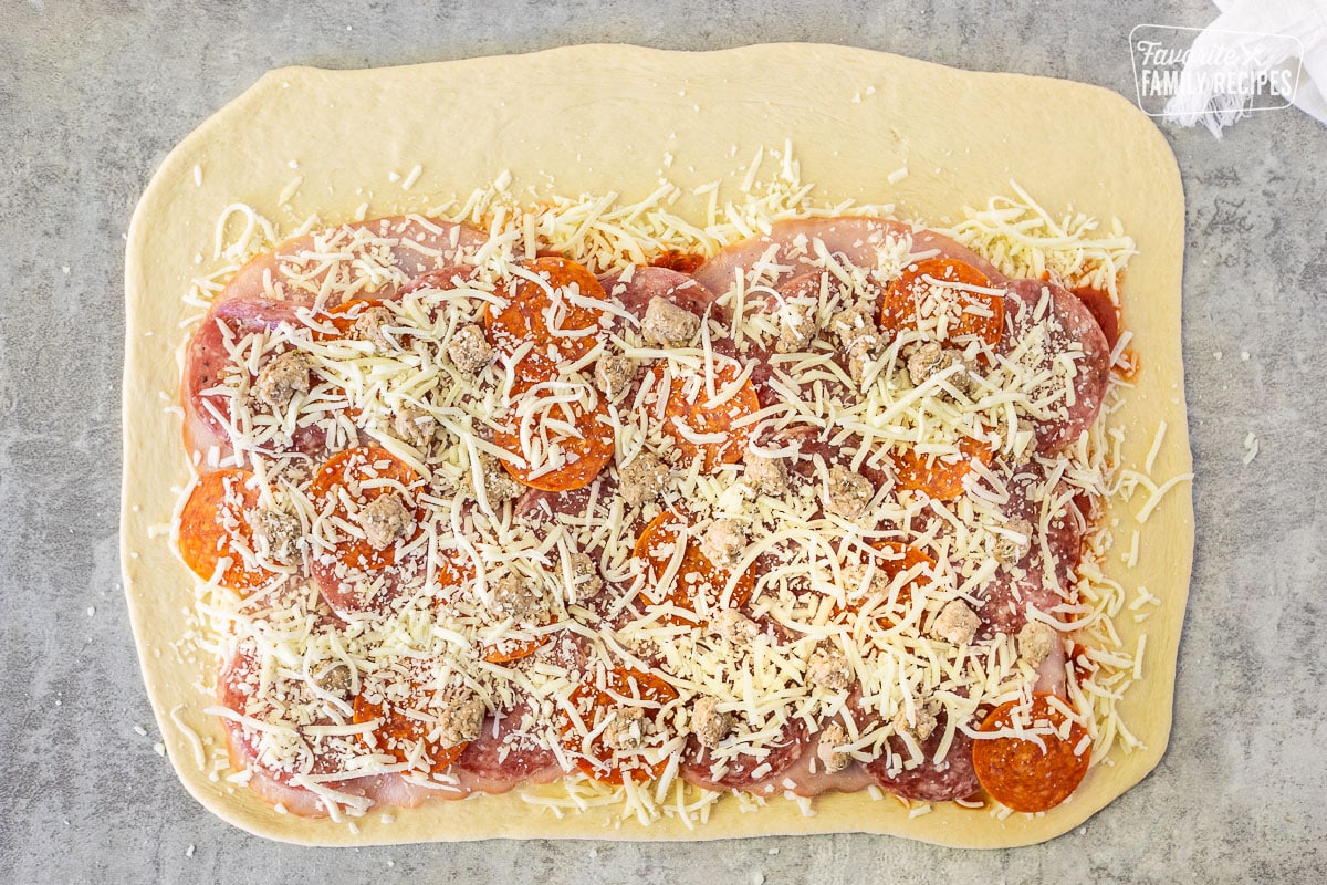 Final cheese topping on meat topping of rolled out dough.