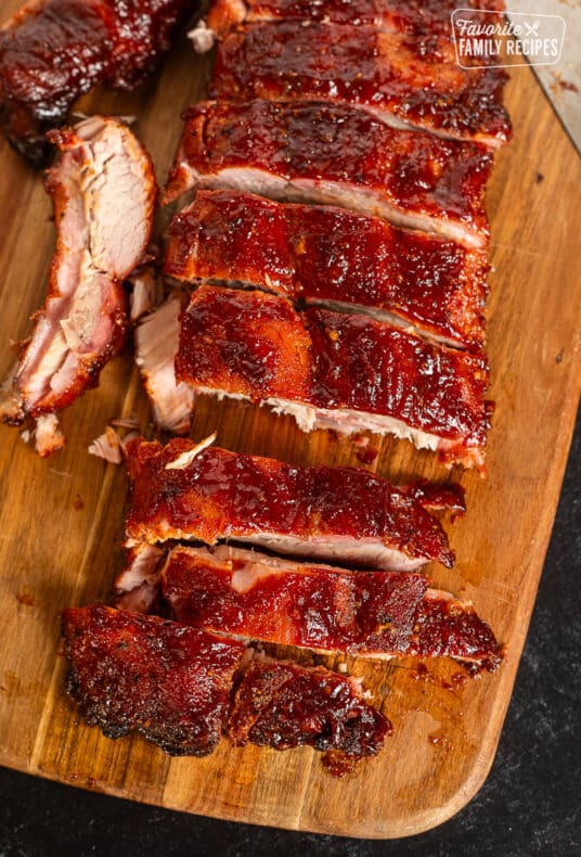 Cut pieces of Smoked Ribs on a cutting board with a knife.