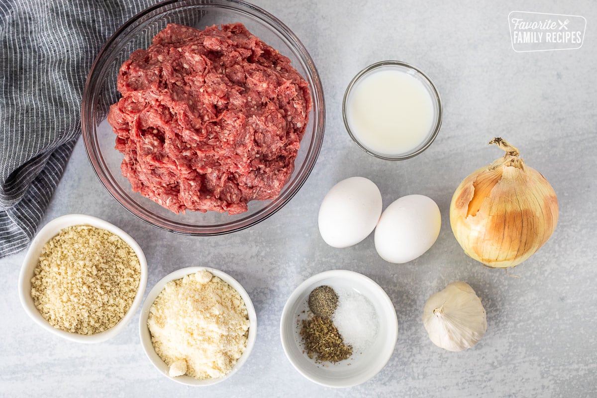 Ingredients to make Air Fryer Meatballs including ground beef, milk, eggs, onion, seasonings, garlic, parmesan cheese and panko crumbs.