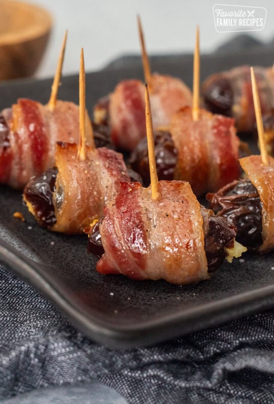 Bacon Wrapped Dates Appetizer with toothpicks on a platter.