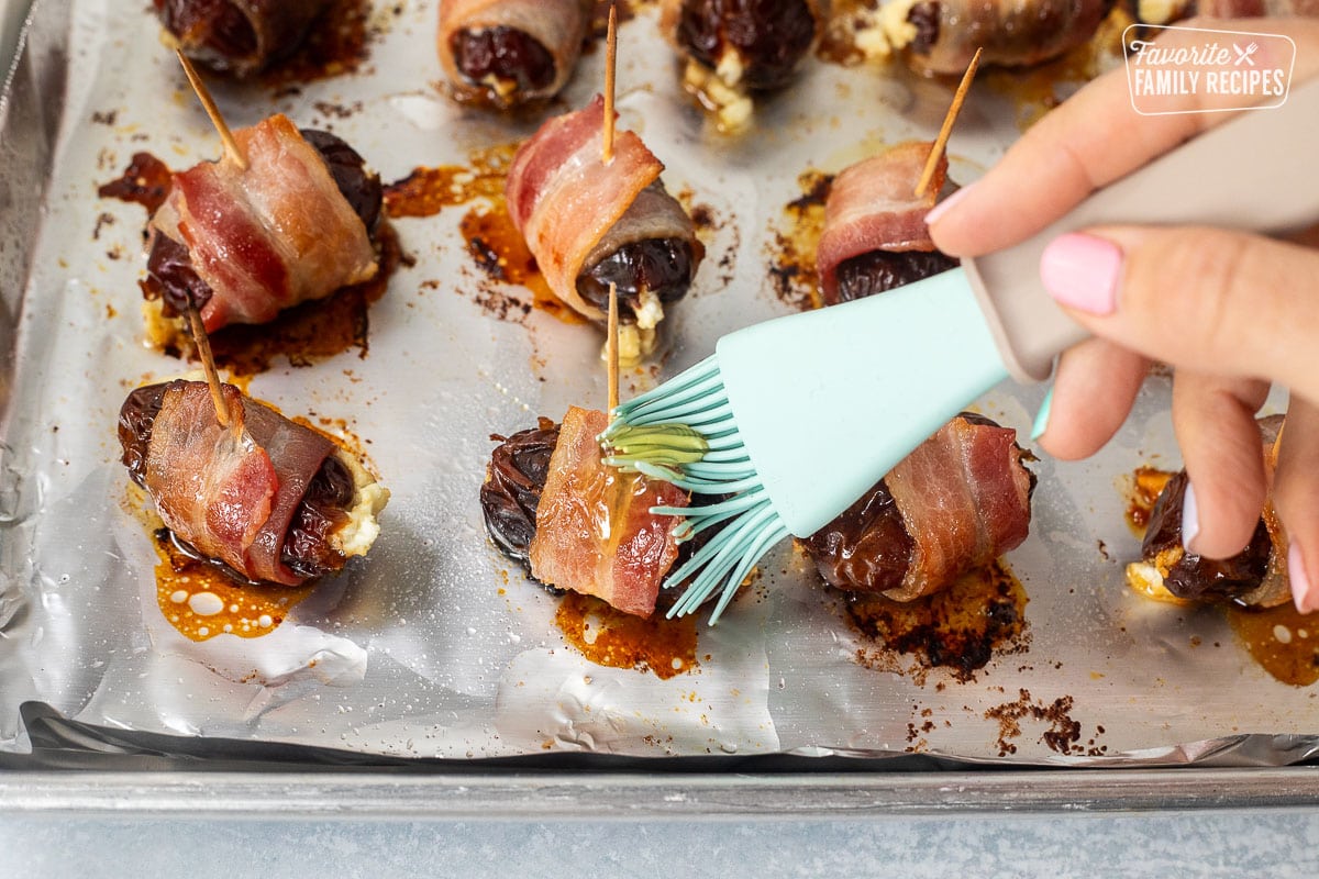 Brushing honey on baked bacon wrapped dates.