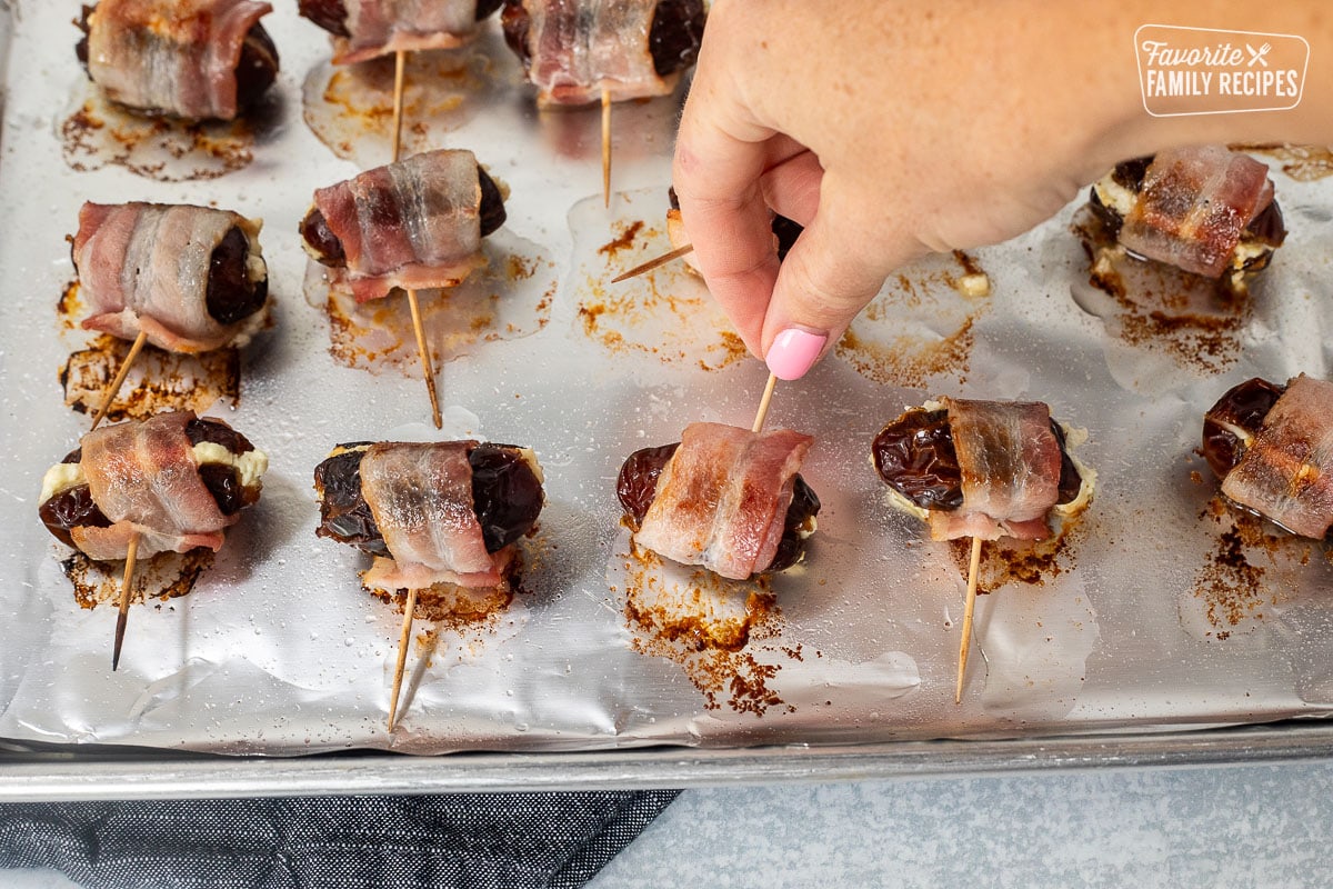 Turning bacon wrapped dates by flipping with toothpick.