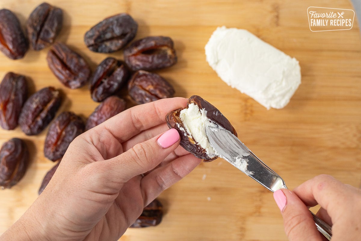 Spreading goat cheese in a date with a small knife.