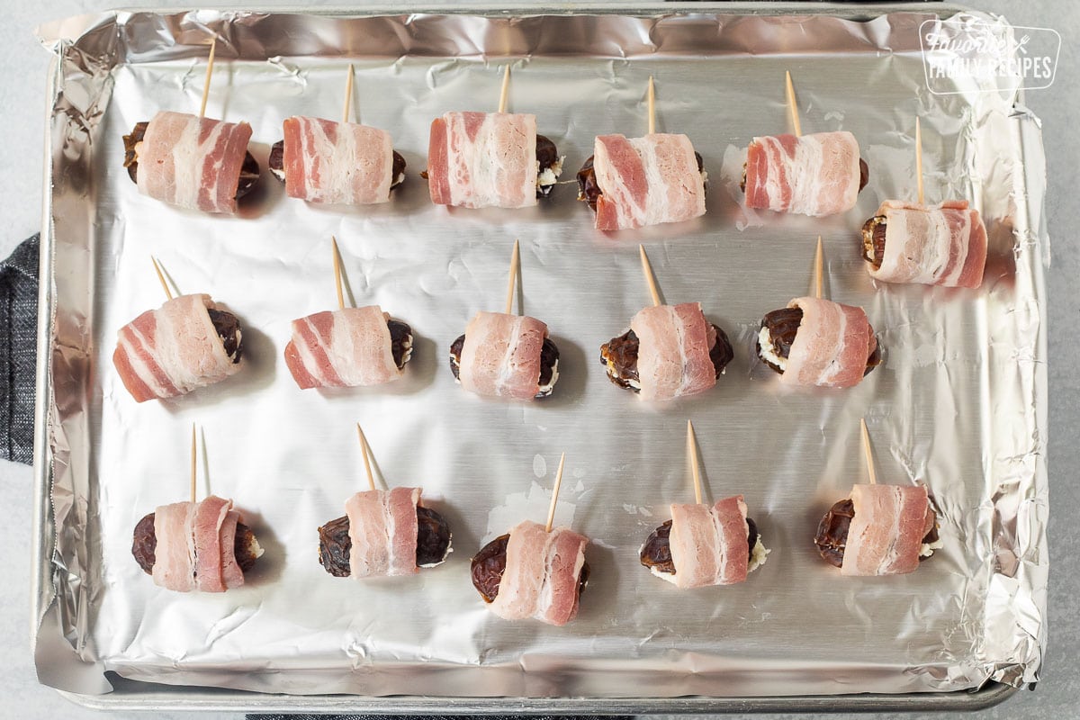 Baking sheet with foil and unbaked bacon wrapped dates.