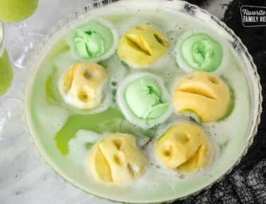 Punch bowl of Halloween drink with apple heads and green lime sherbet.