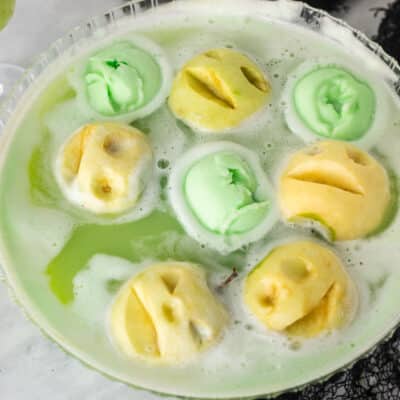 Punch bowl of Halloween drink with apple heads and green lime sherbet.