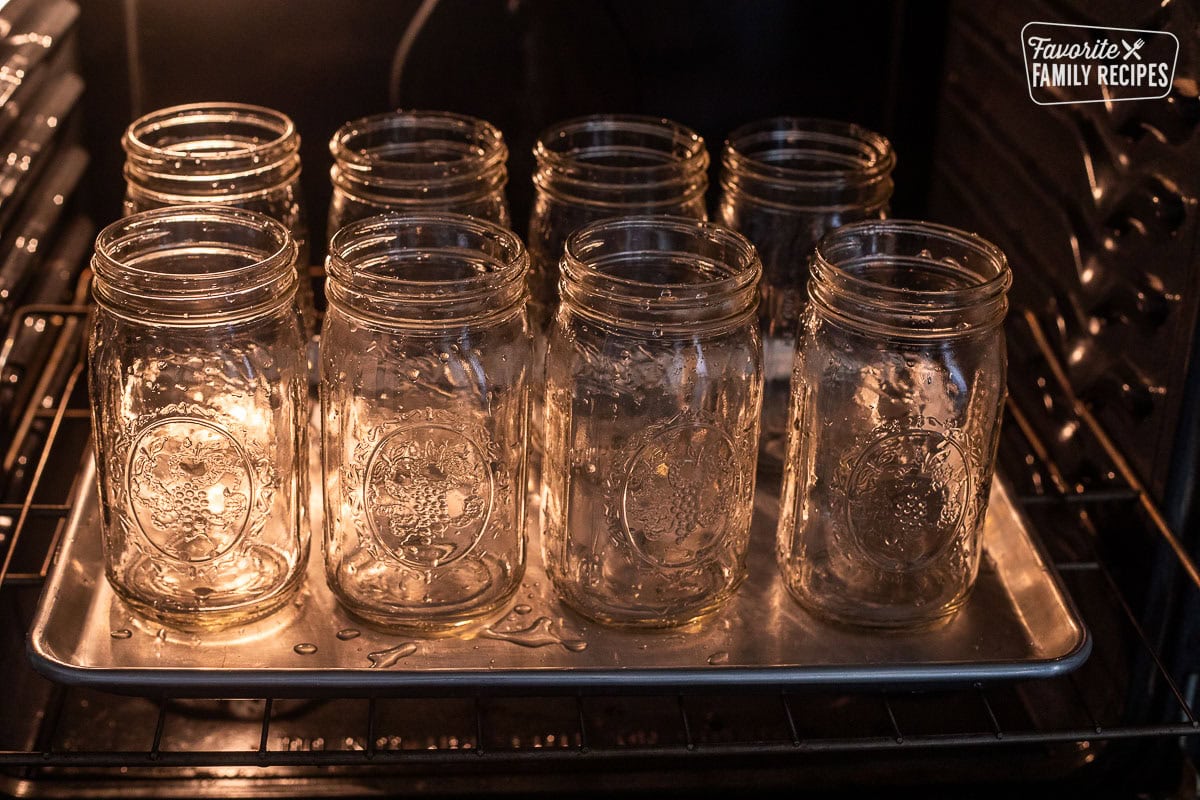 Oven with wet canning jars on a baking sheet.