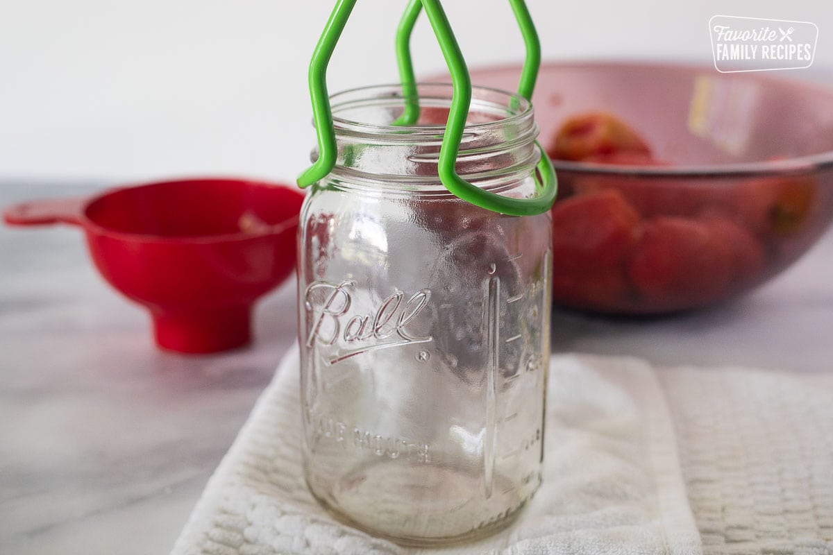 Canning jar with a jar lifter wrapped around the top rim.