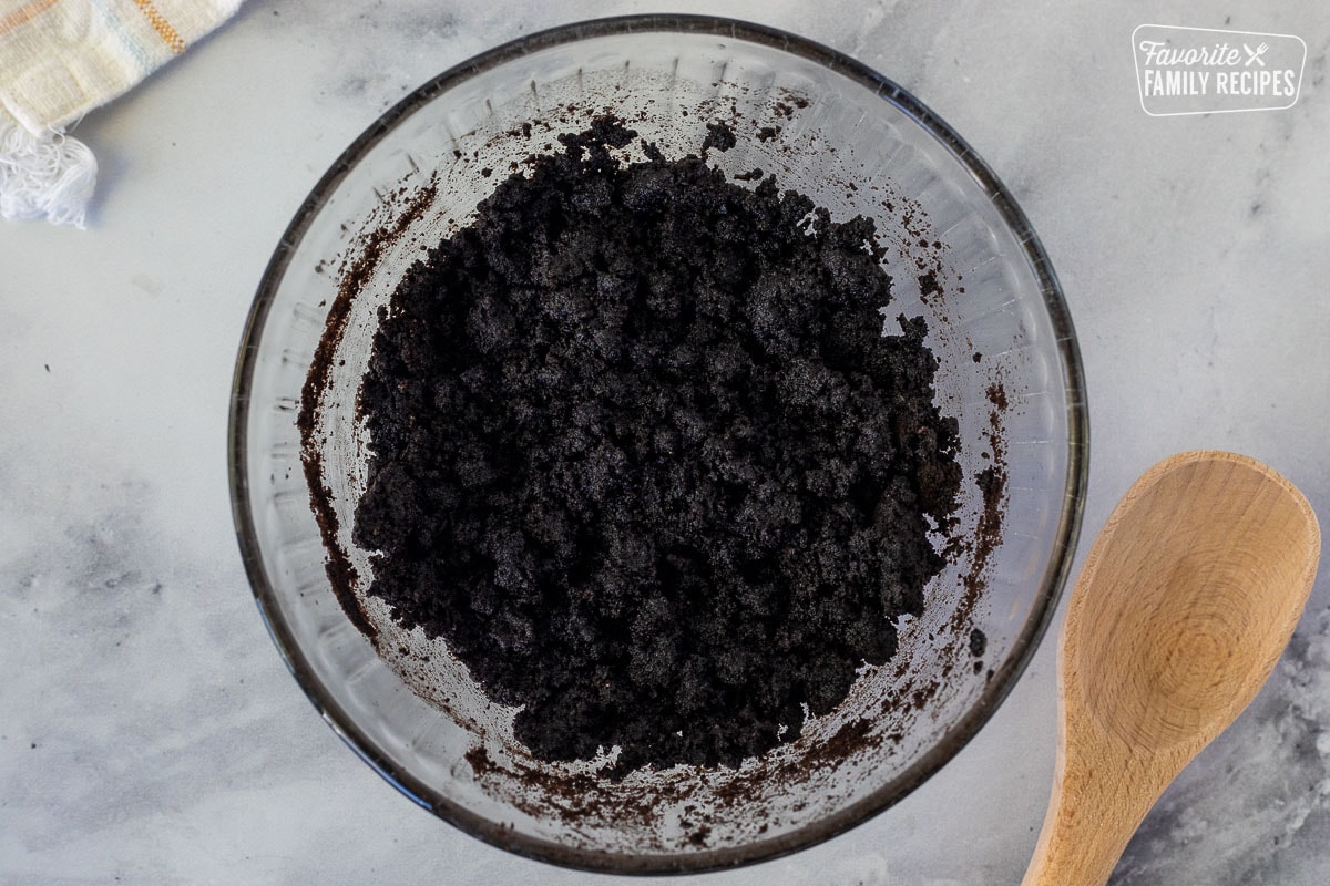 Oreo and butter mixture in a glass bowl for Chocolate Satin Pie crust.