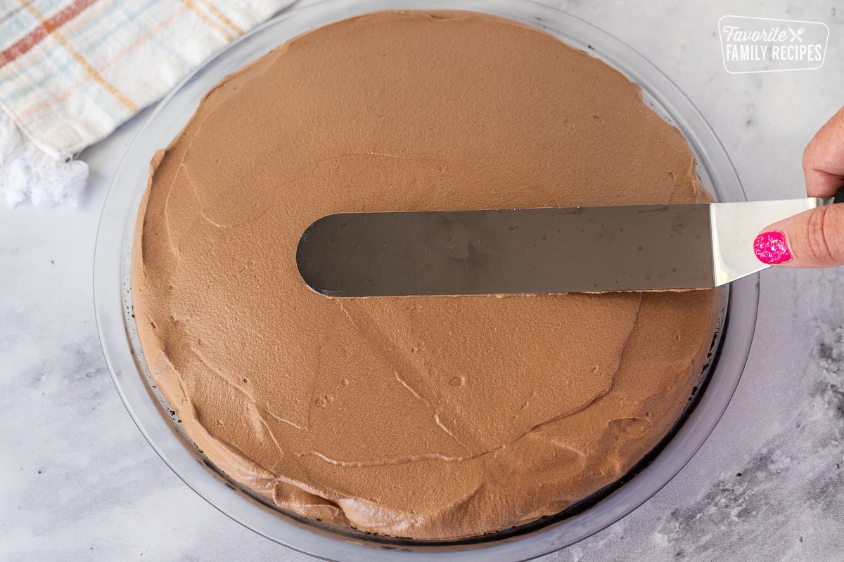 Smoothing top of Chocolate Satin Pie with a flat spatula.