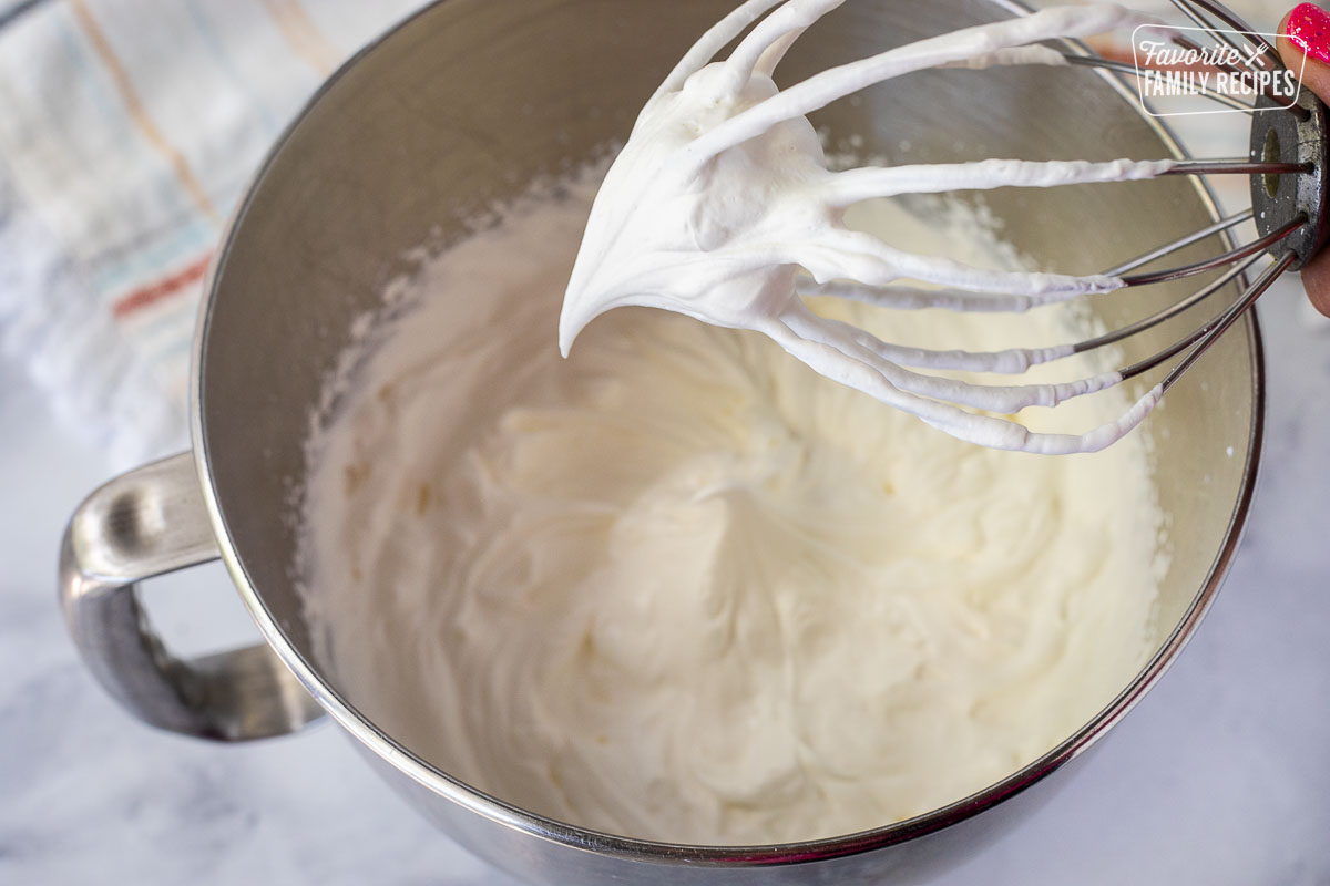 Mixing bowl of whipped cream with mixer whisk for Chocolate Satin Pie.