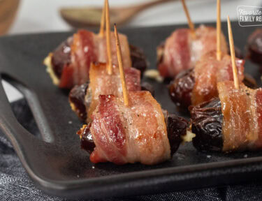 Bacon Wrapped Dates Appetizer with toothpicks on a platter.