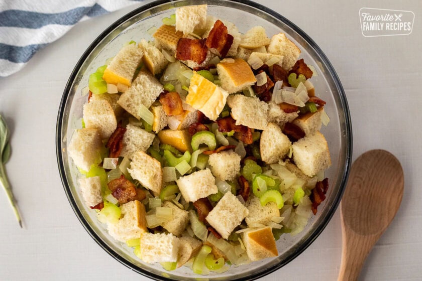 Mixing bowl with cubed bread, bacon, cooked celery and onion.