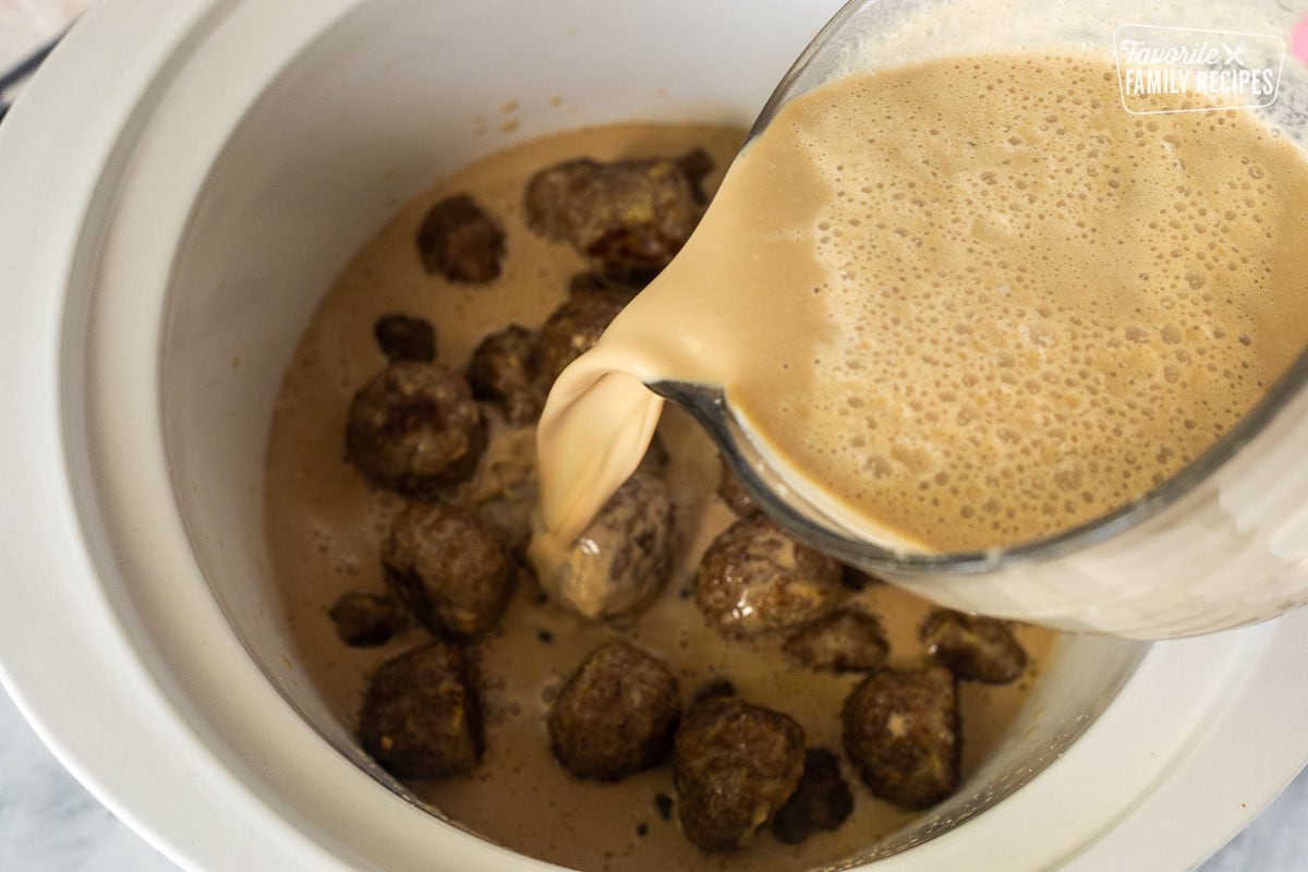 Pouring sauce in crock pot of cooked meatballs.