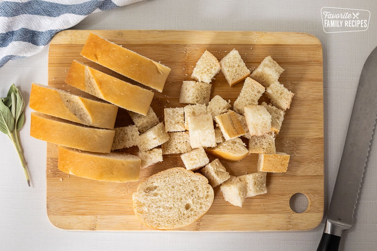 Cutting board with cubed pieces of French bread.