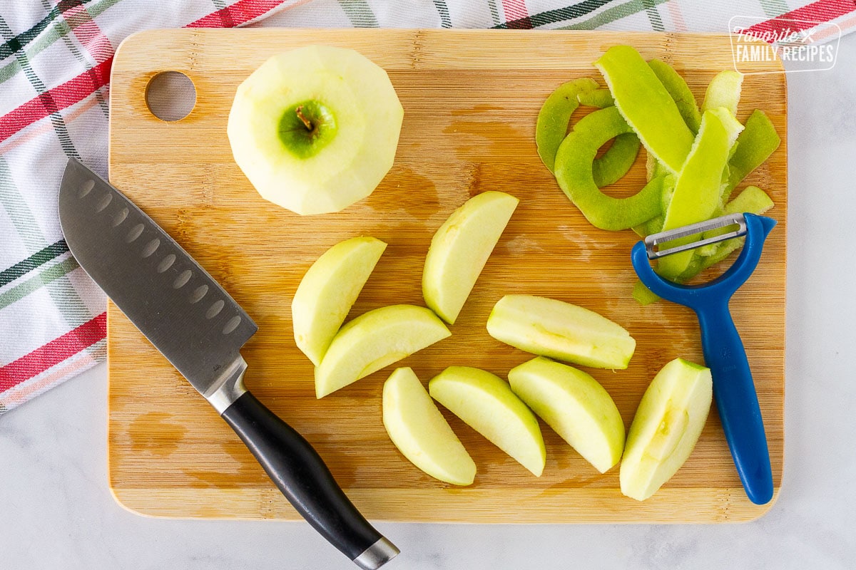 Cutting board with peels and sliced green apples for Apple Dumplings.