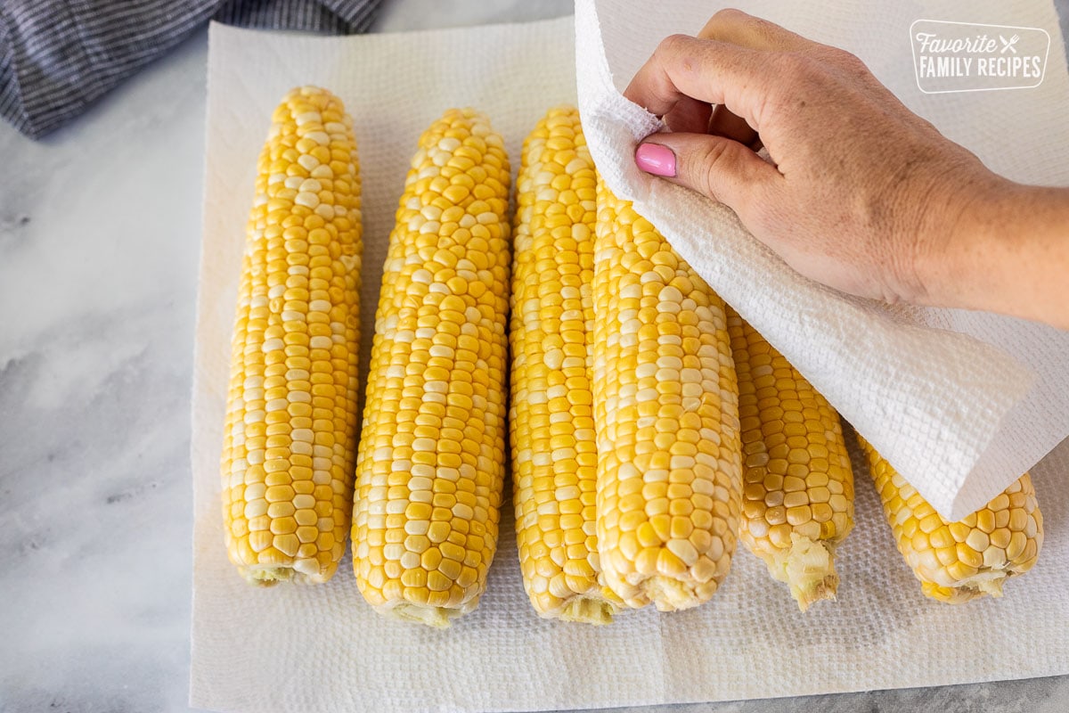 Patting the cobs of corn dry with a paper towel.