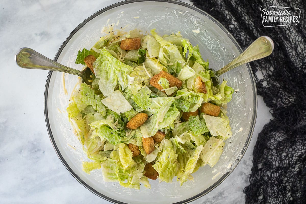 Bowl of mixed Cesar salad with forks.