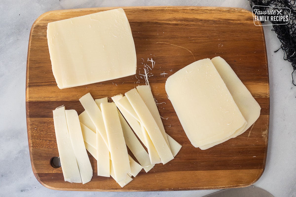 Cutting board with strips of mozzarella cheese sliced.