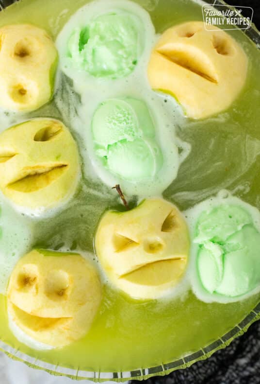 Halloween Punch in a bowl with floating apple heads and scoops of lime sherbet.