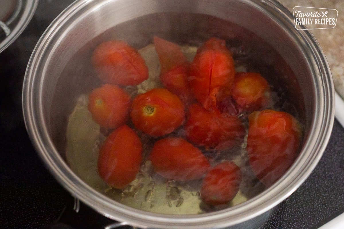 Pot of boiling water with tomatoes.