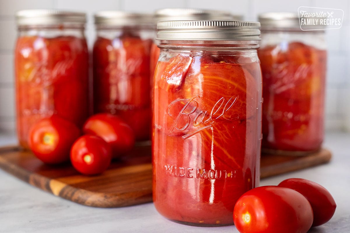 Canning jar with whole tomatoes. Roma tomatoes on the side.