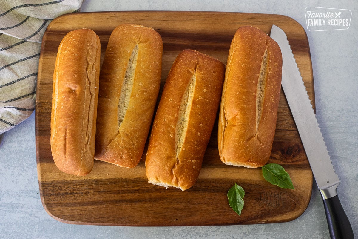 Rolls cut in half on cutting board with knife.