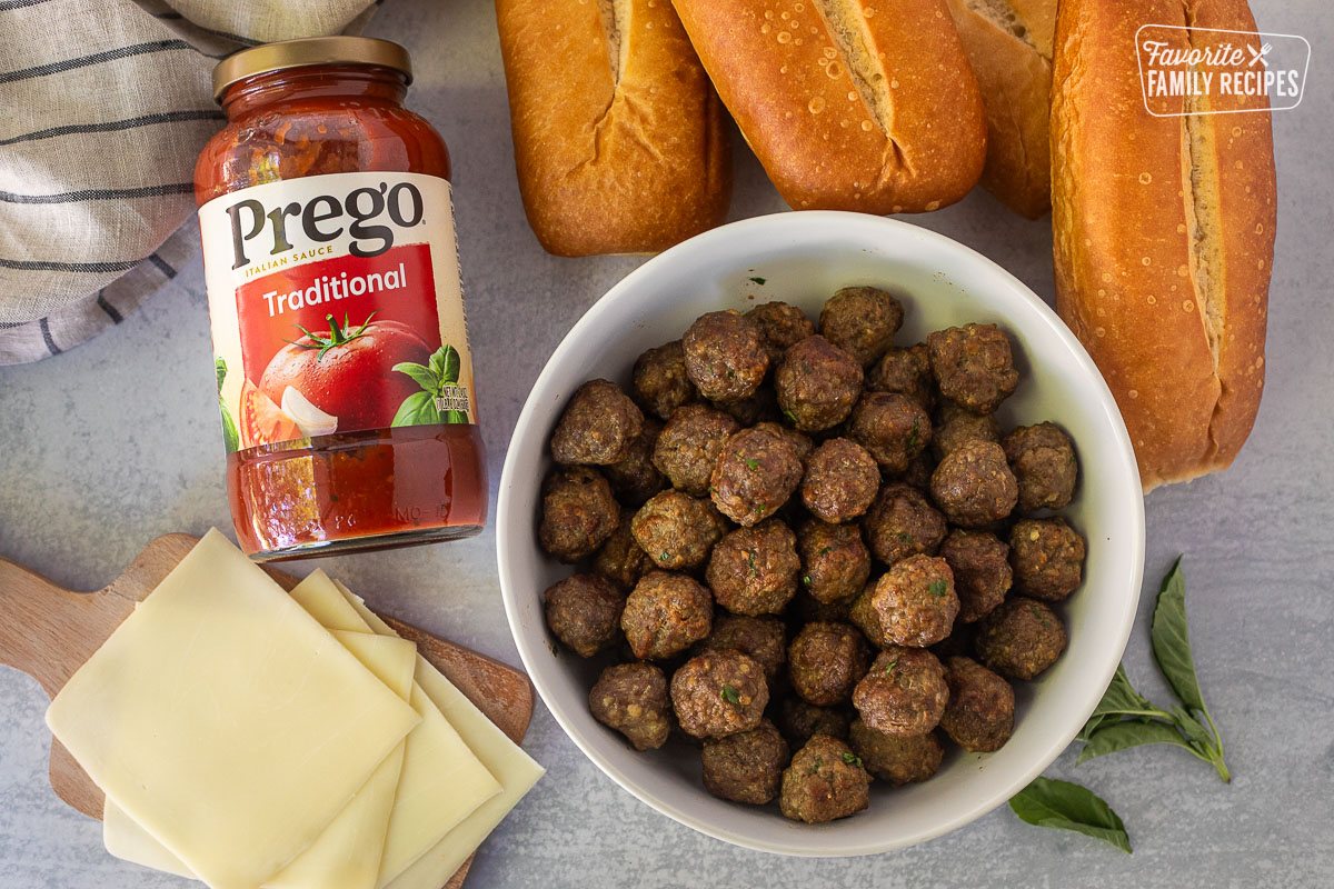 Ingredients to make Meatball Sandwiches including rolls, marinara sauce, provolone cheese and meatballs.