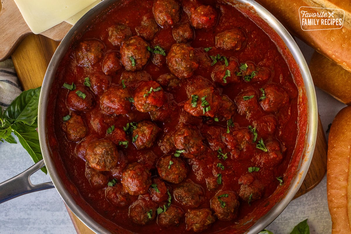 Meatballs in skillet with marinara sauce and basil.