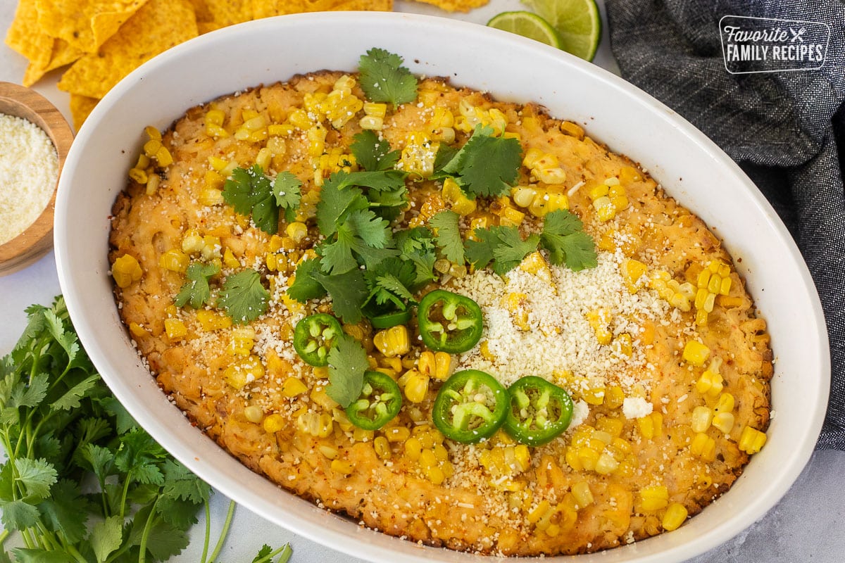 Baked Mexican Street Corn Dip in a dish toped with jalapeño, cilantro and cojita cheese.