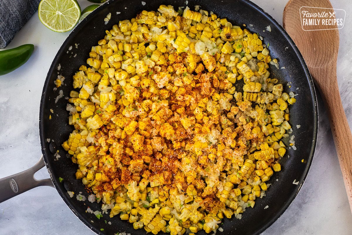 Skillet with seasoning on grilled corn mixture.